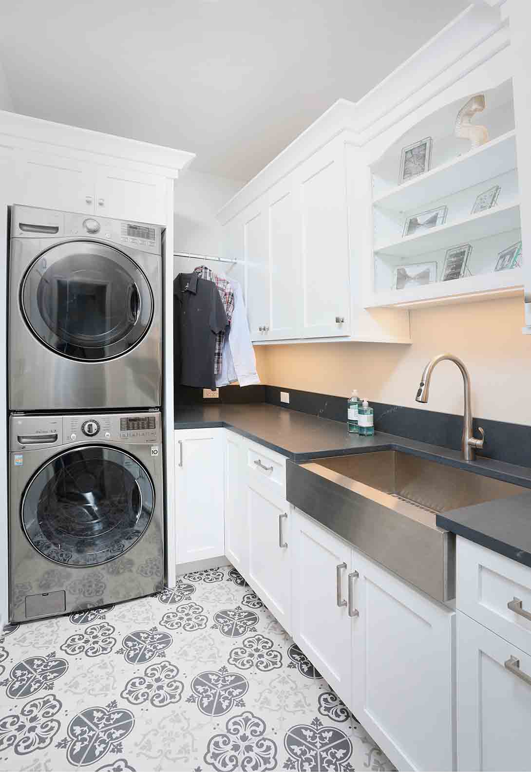 laundry room with stainless steel apron front sink and stacked washer